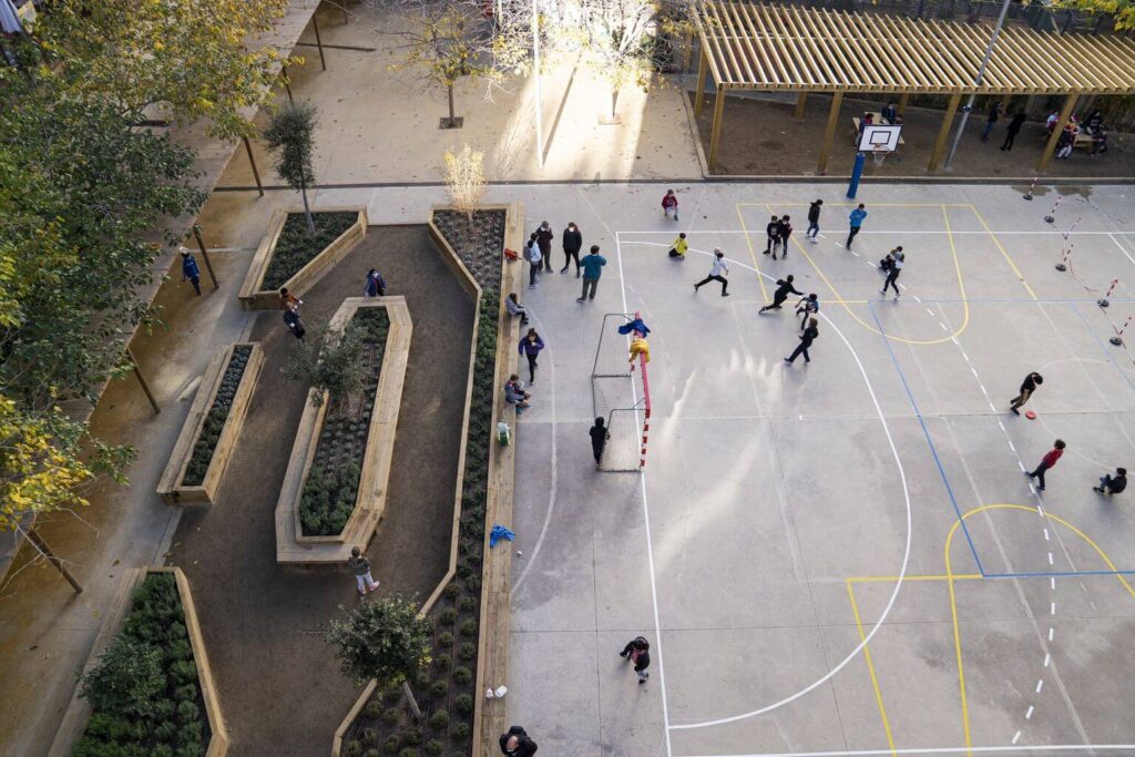 Patio de escuela visto desde arriba. Niños jugando futbol