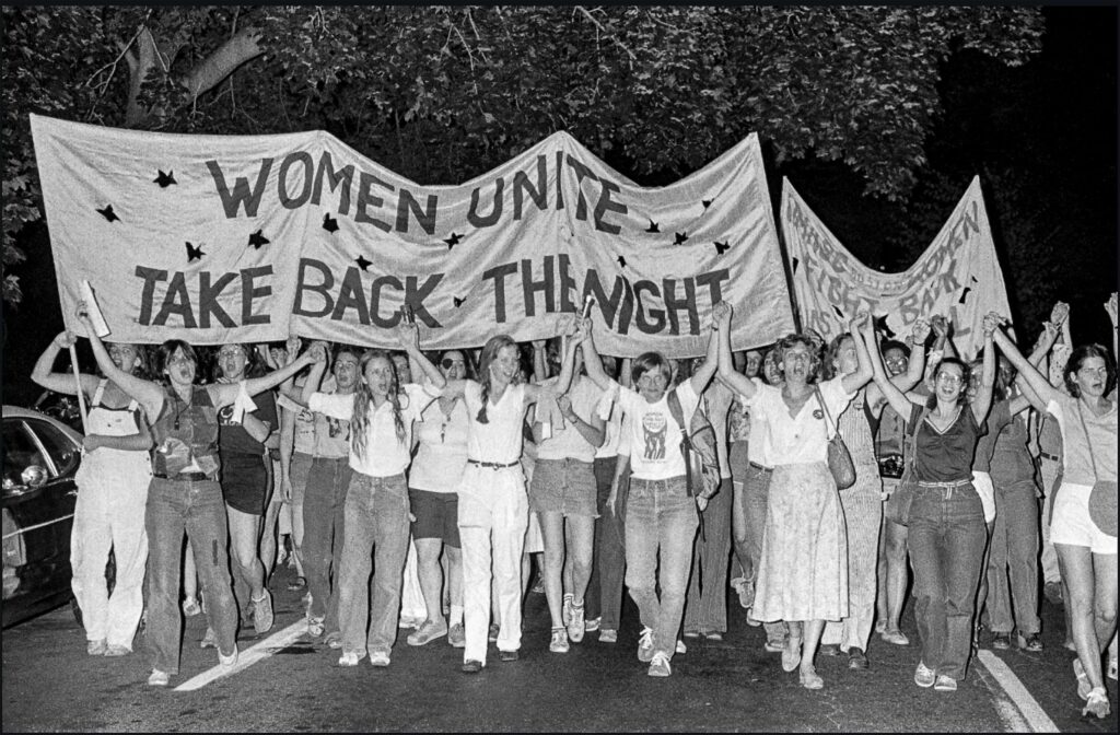 Mujeres reunidas en una manifestación de Take Back the Night en Boston, MA en 1979. Sosteniendo pancarta que se lee: "Mujeres Unidas. Tomemos la noche"