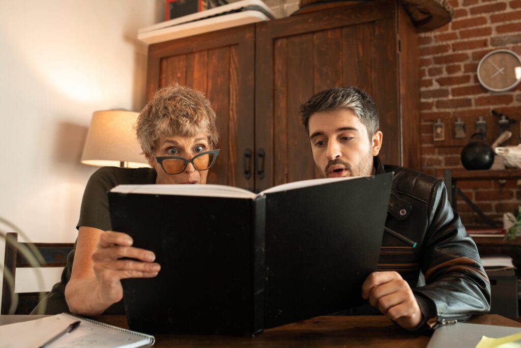 Adultos sorprendidos leen un libro juntos.