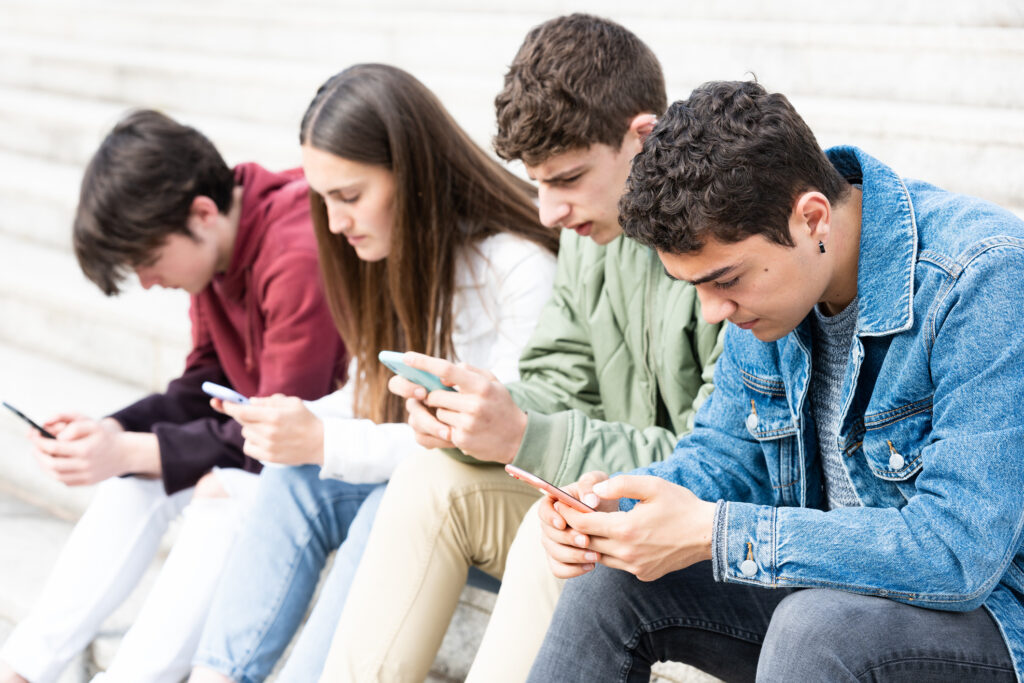 Adolescentes usando su teléfono con amigos